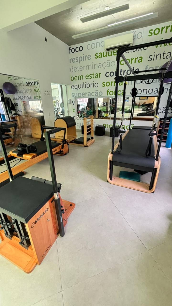 Sala de Pilates em Moema com aparelhos de madeira, uma torre com barras e espelhos na parede